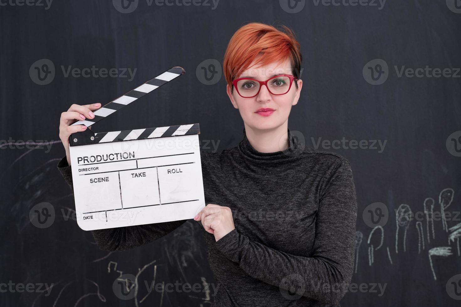 redhead woman holding clapper on black background photo