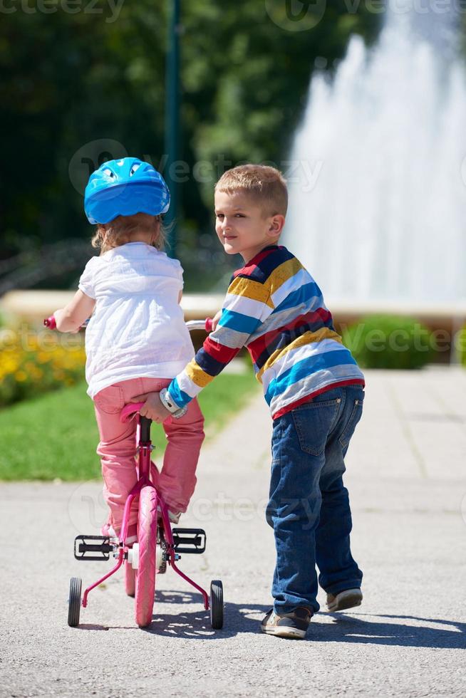 Boy and girl in park learning to ride a bike photo