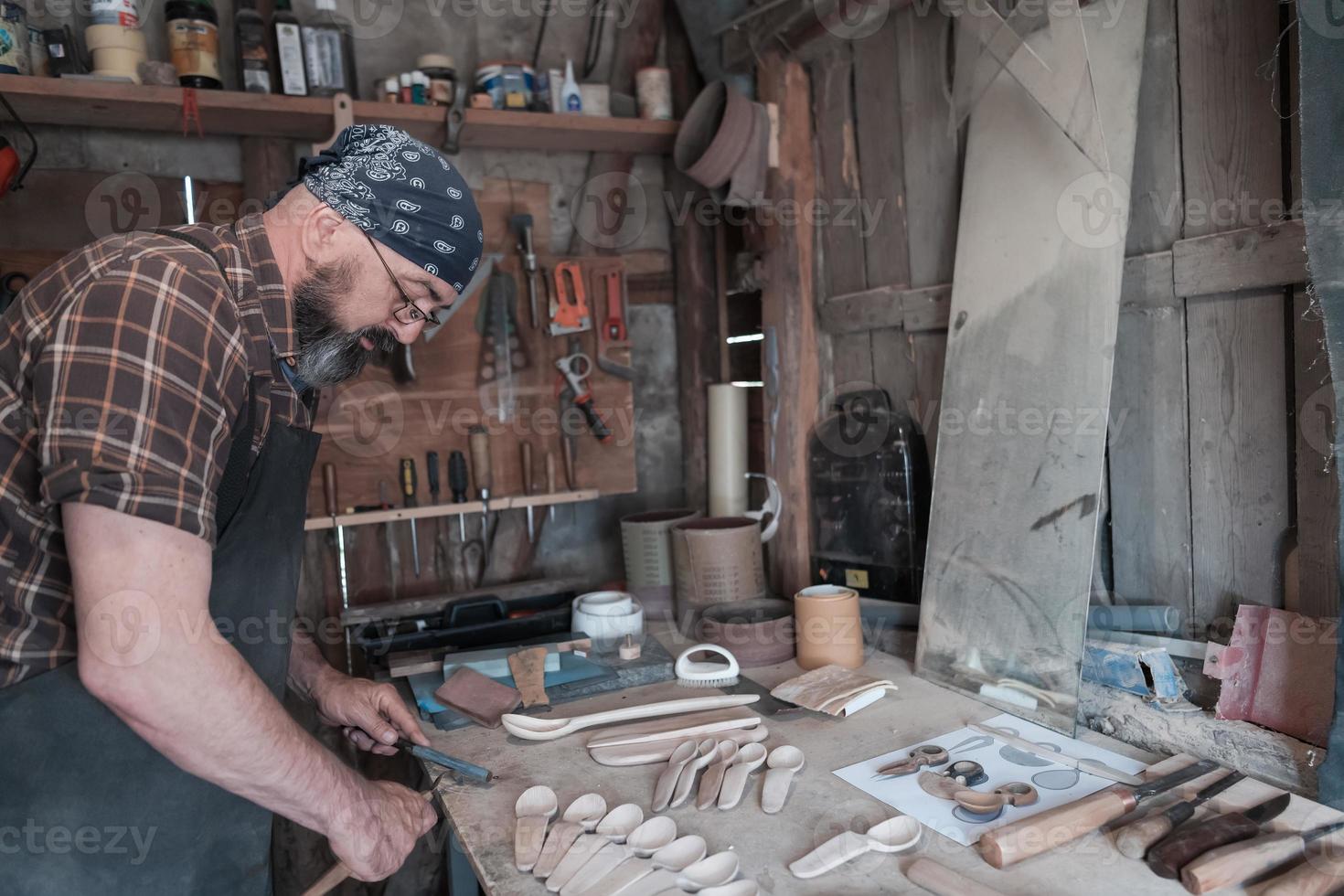 Spoon master in his workshop with wooden products and tools photo