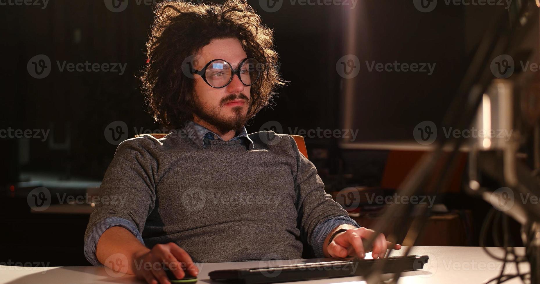 man working on computer in dark office photo