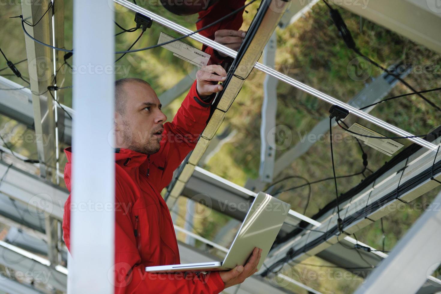 engineer using laptop at solar panels plant field photo