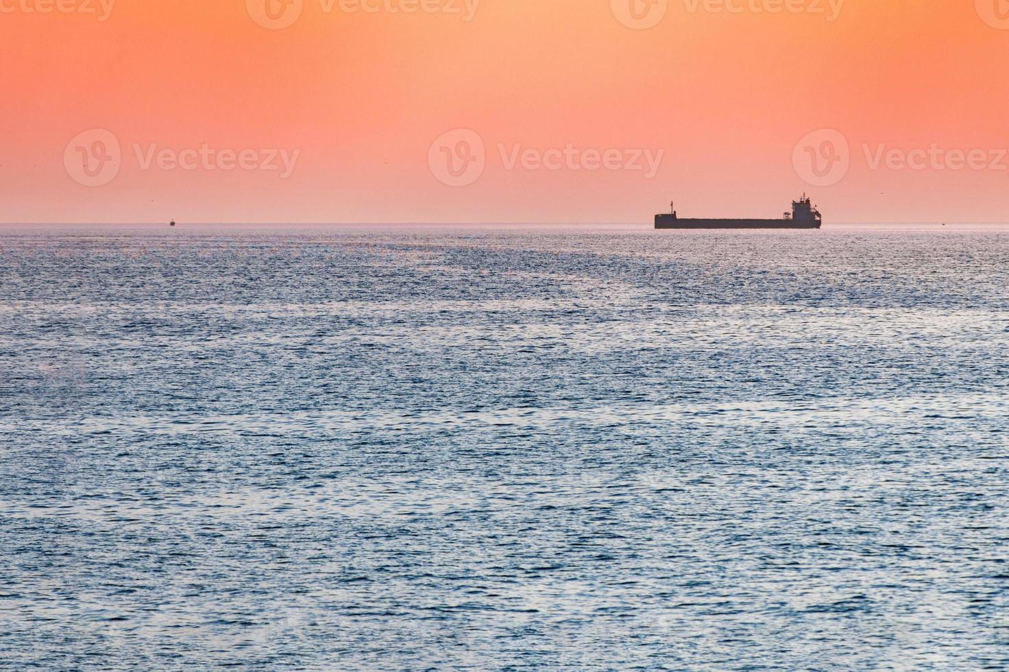 Little tugboat and big cargo ship. Beautiful sunset over sea. Breathtaking travel view, copy space. photo