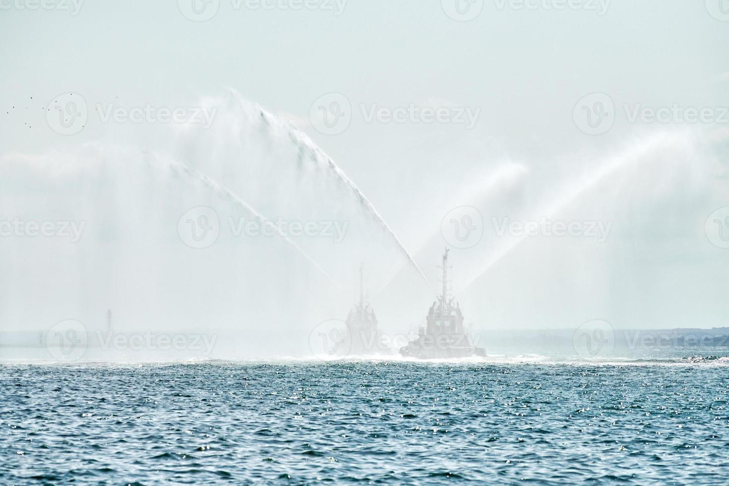 remolcadores rociando chorros de agua, demostrando cañones de agua contra incendios, botes de bomberos rociando espuma foto