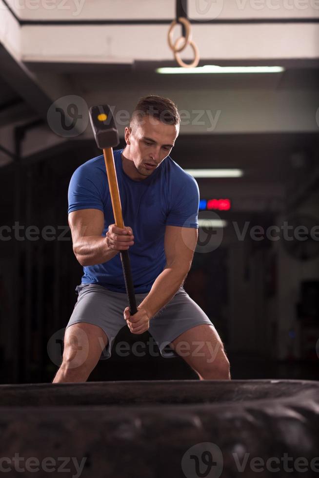 man workout with hammer and tractor tire photo