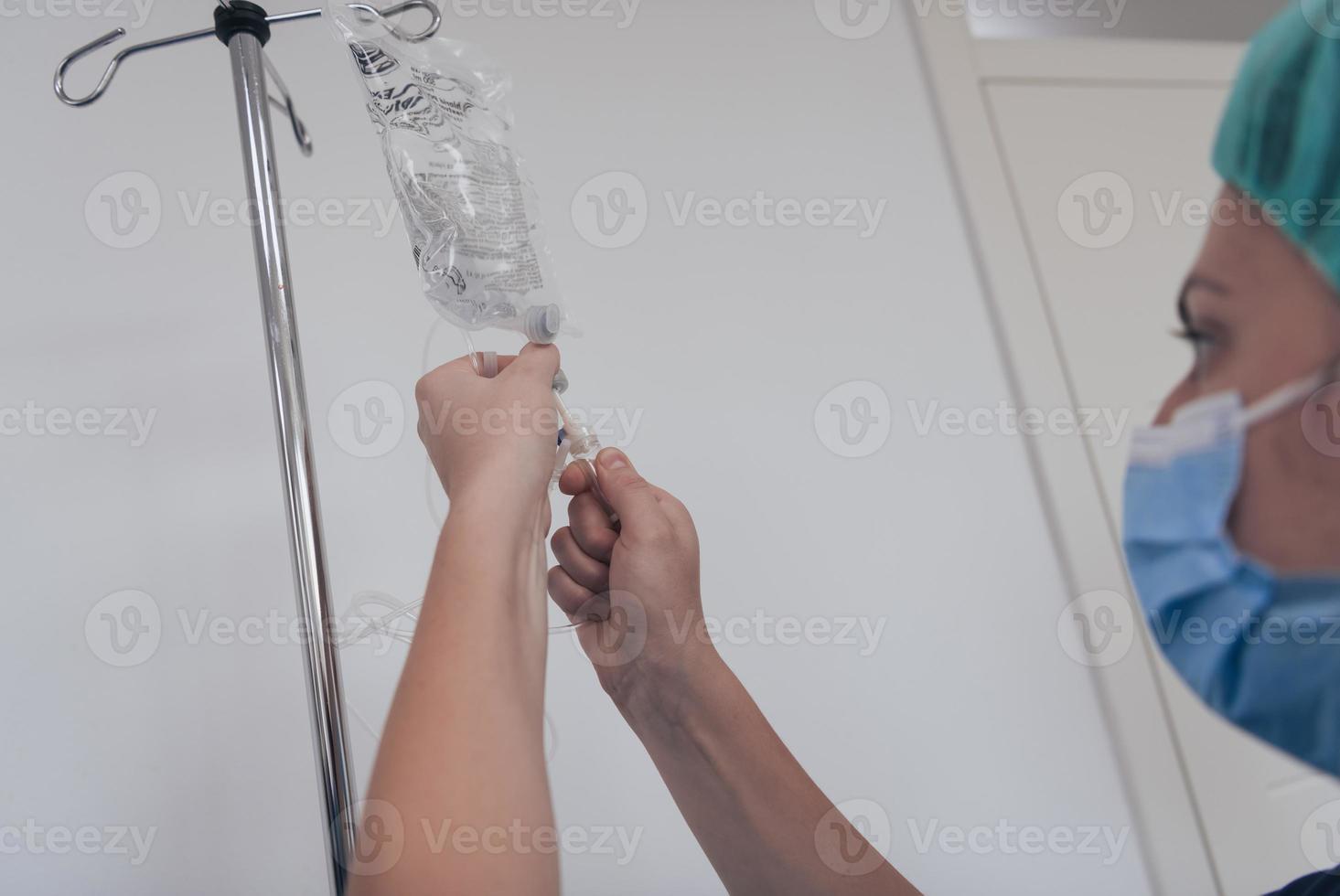 General practitioner holding intravenous drip infusion. Doctor handling IV fluid drip with copy space on white background. Nurse performing Intravenous therapy. photo