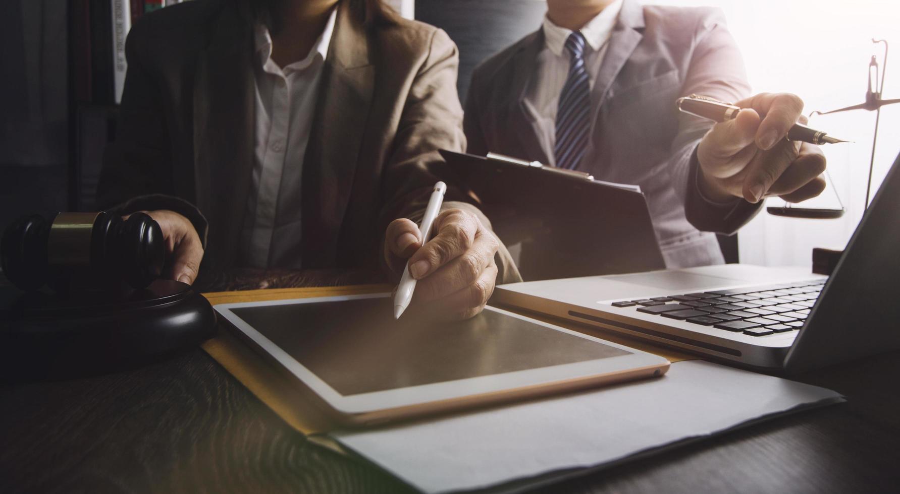 Business and lawyers discussing contract papers with brass scale on desk in office. Law, legal services, advice, justice and law concept picture with film grain effect photo