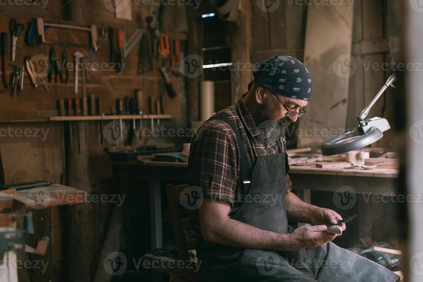 Spoon master in his workshop with wooden products and tools photo