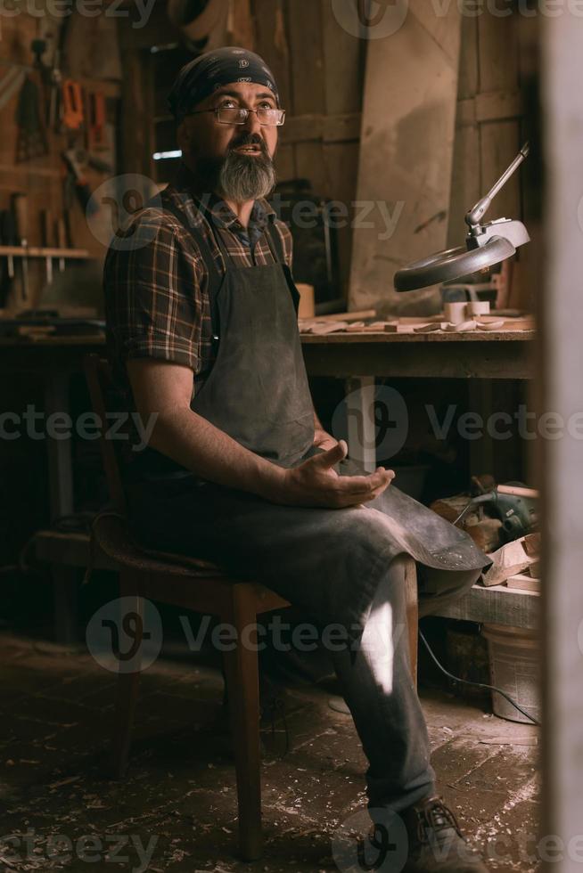 maestro de cucharas en su taller con productos y herramientas de madera foto