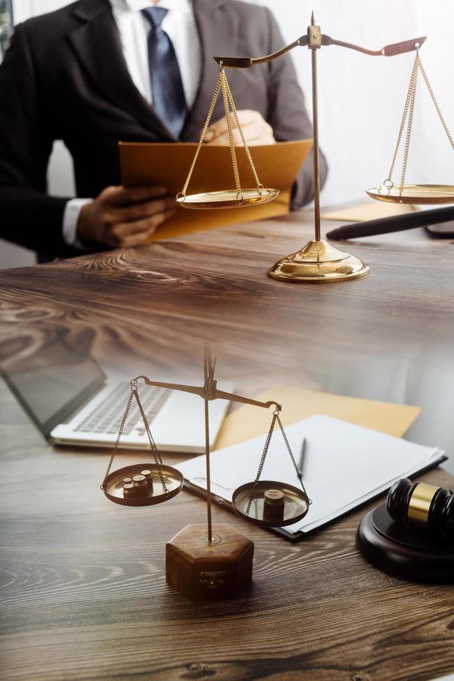 Business and lawyers discussing contract papers with brass scale on desk in office. Law, legal services, advice, justice and law concept picture with film grain effect photo