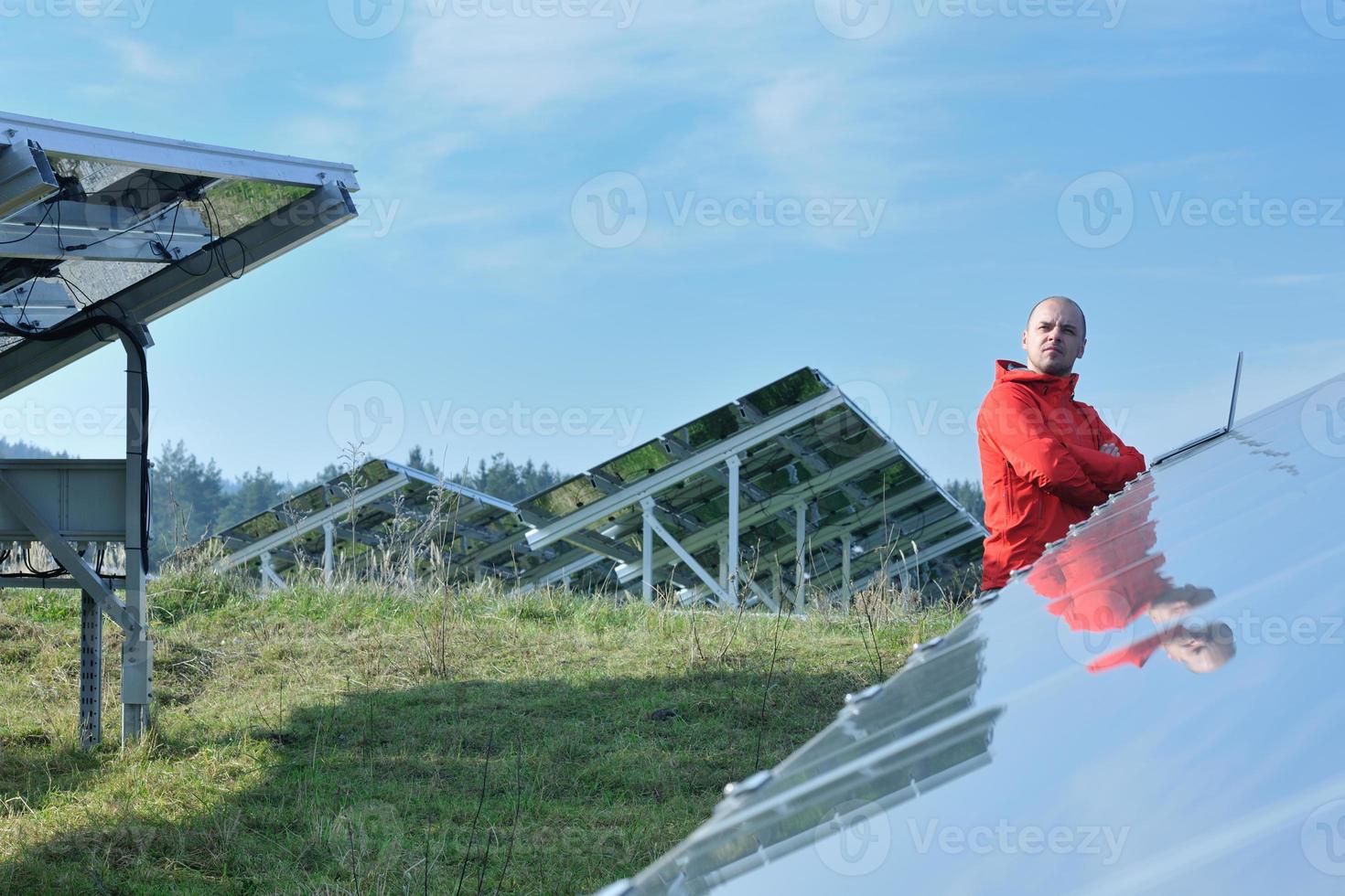 engineer using laptop at solar panels plant field photo