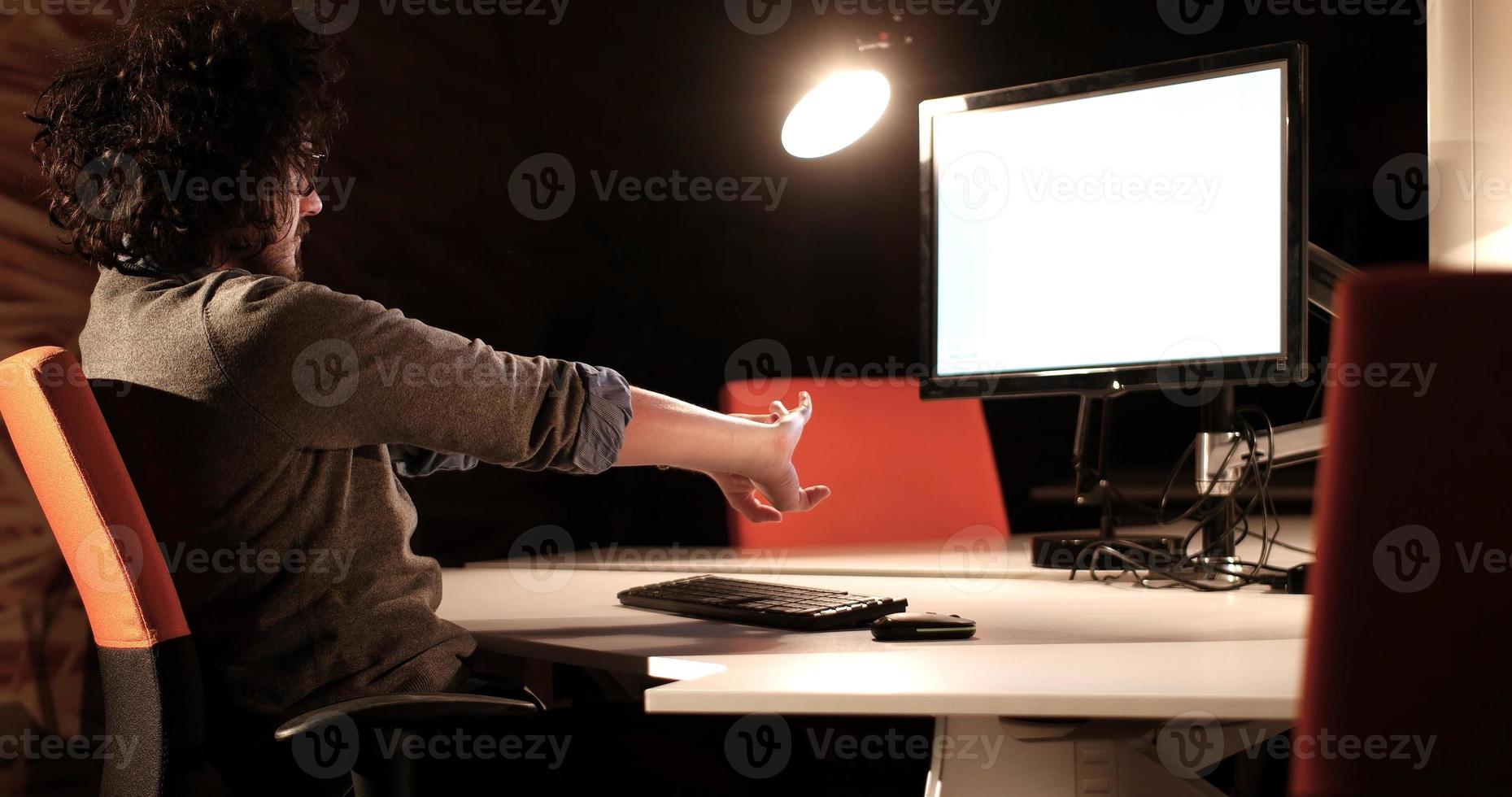 man working on computer in dark office photo