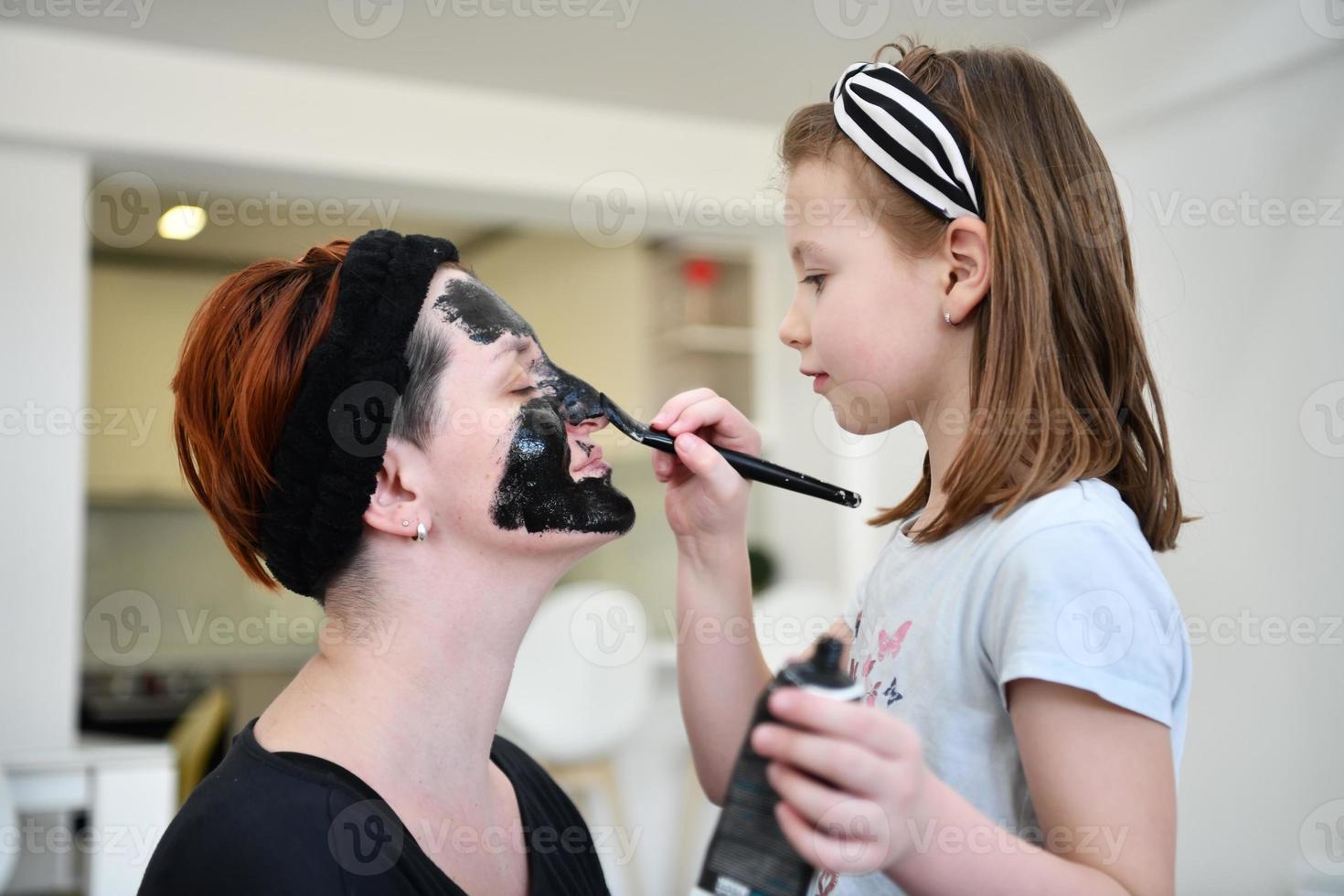mother and daughter at home making facial mask beauty treatment photo