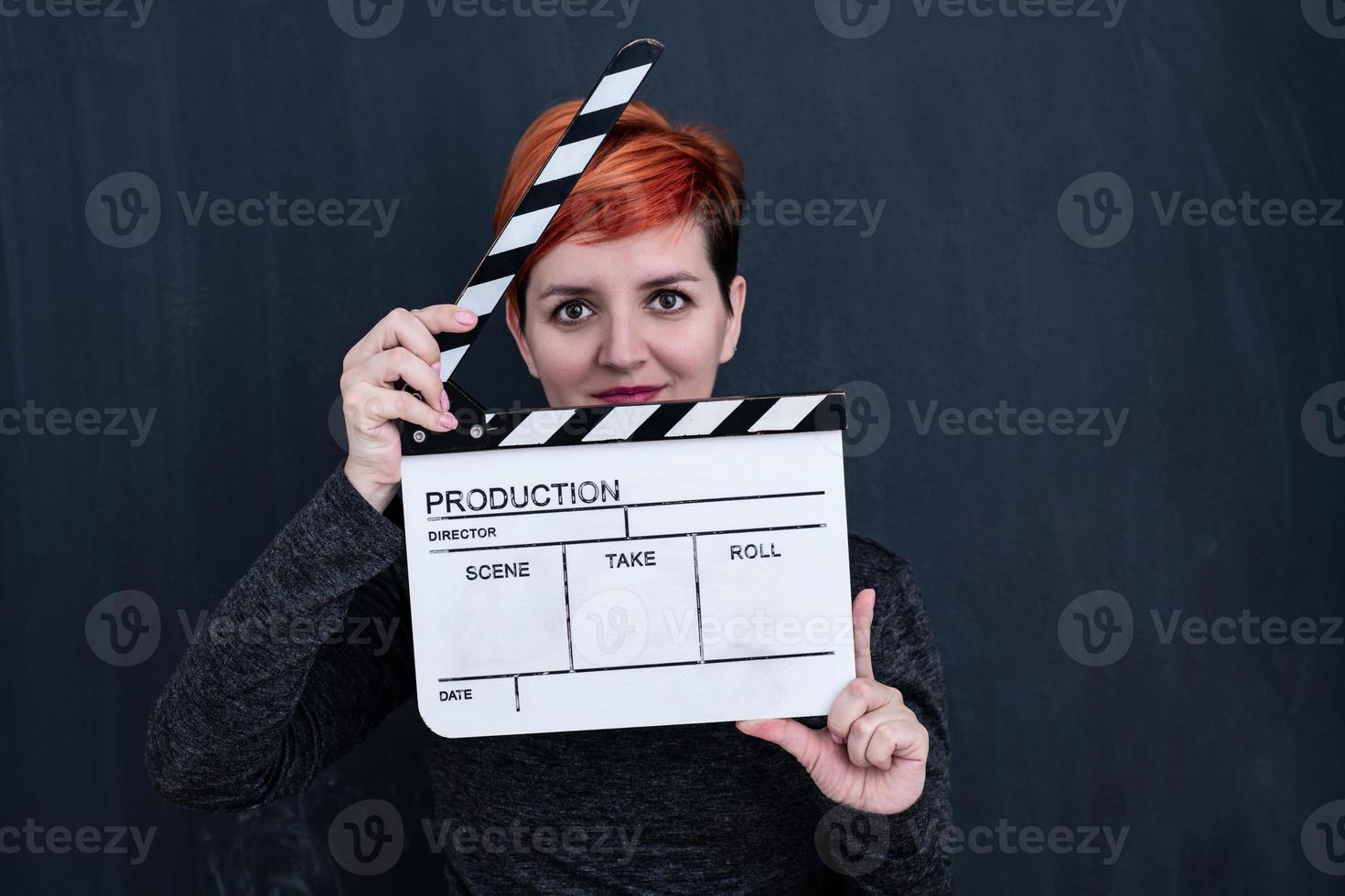 redhead woman holding movie clapper photo