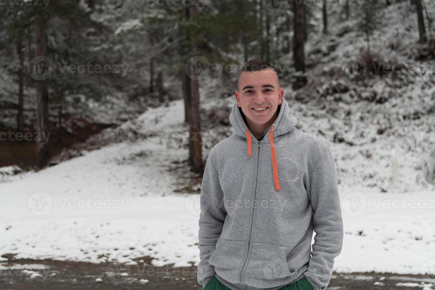 A portrait of a young man in a snowy forest dressed in casual clothes. Selective focus photo