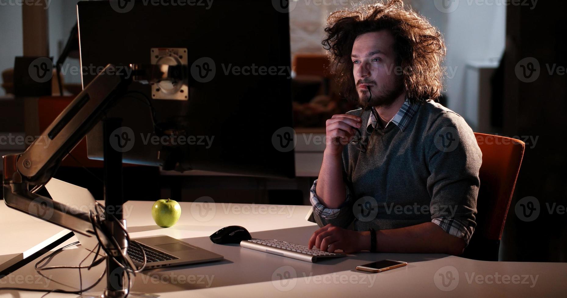 man working on computer in dark office photo