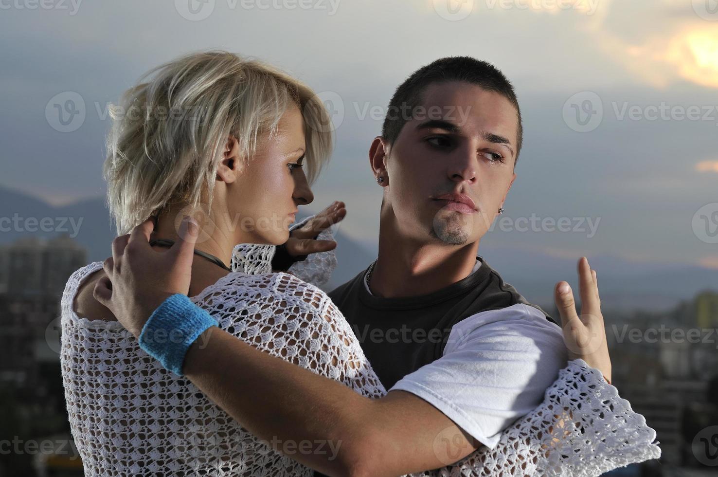 romantic urban couple dancing on top of the bulding photo