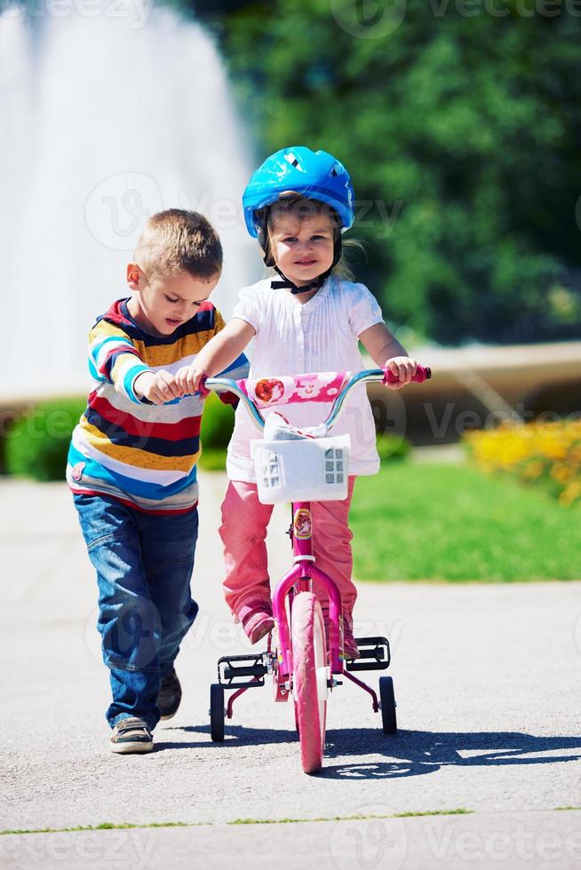Boy and girl in park learning to ride a bike photo