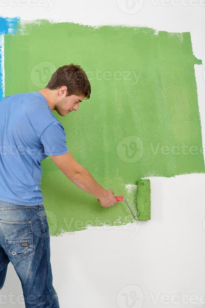 handsome young man paint white wall in color photo