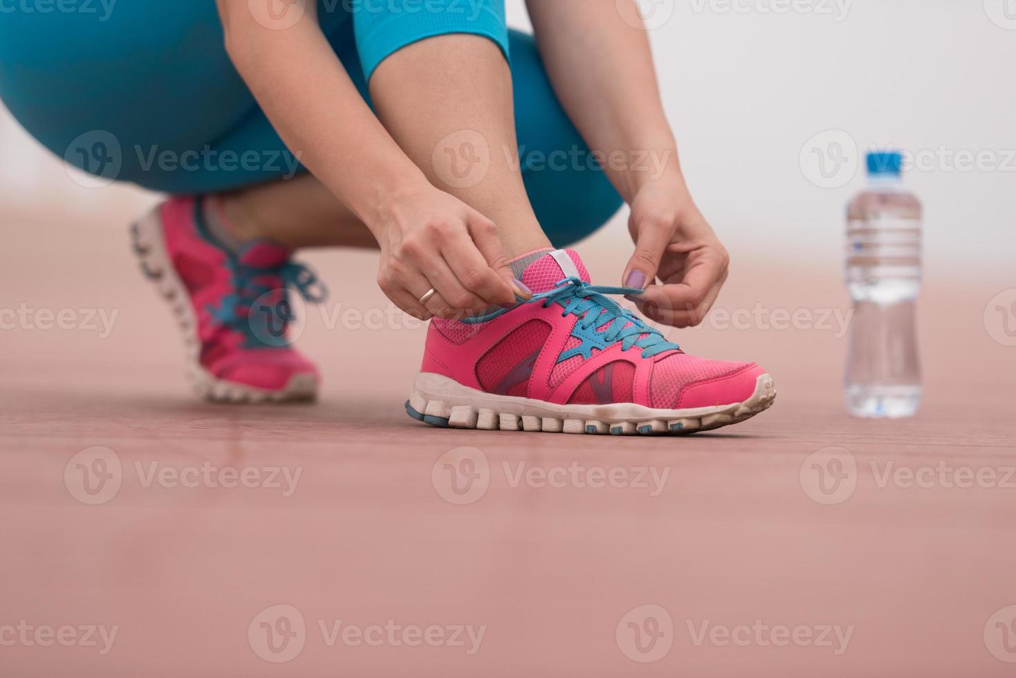 Young woman tying shoelaces on sneakers photo