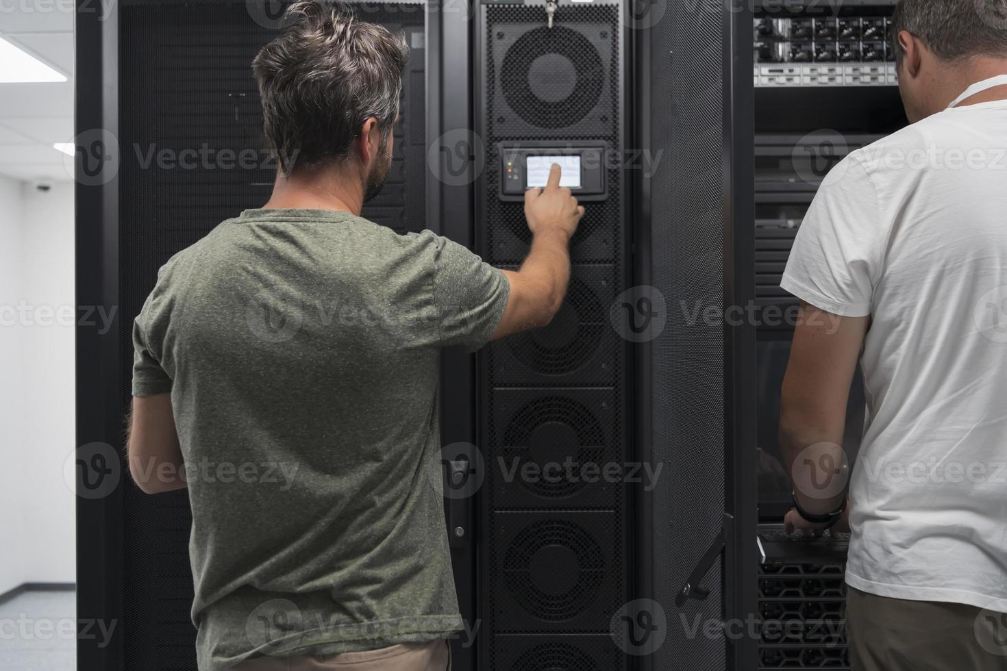 Data Center Engineer Using Laptop Computer. Server Room Specialist Facility with Korean Male System Administrator Working with Data Protection Network for Cyber Security. photo