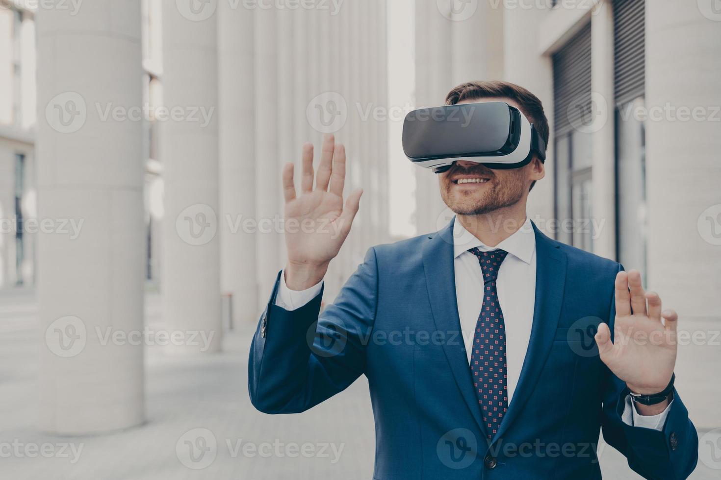 Professional male architect in augmented reality headset gesturing while standing outdoors photo