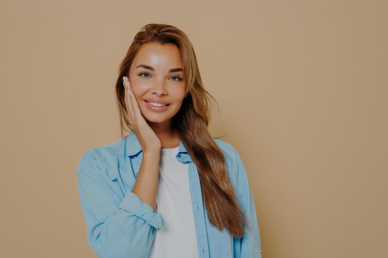 una mujer encantadora tocándose la cara con una piel limpia y sana foto