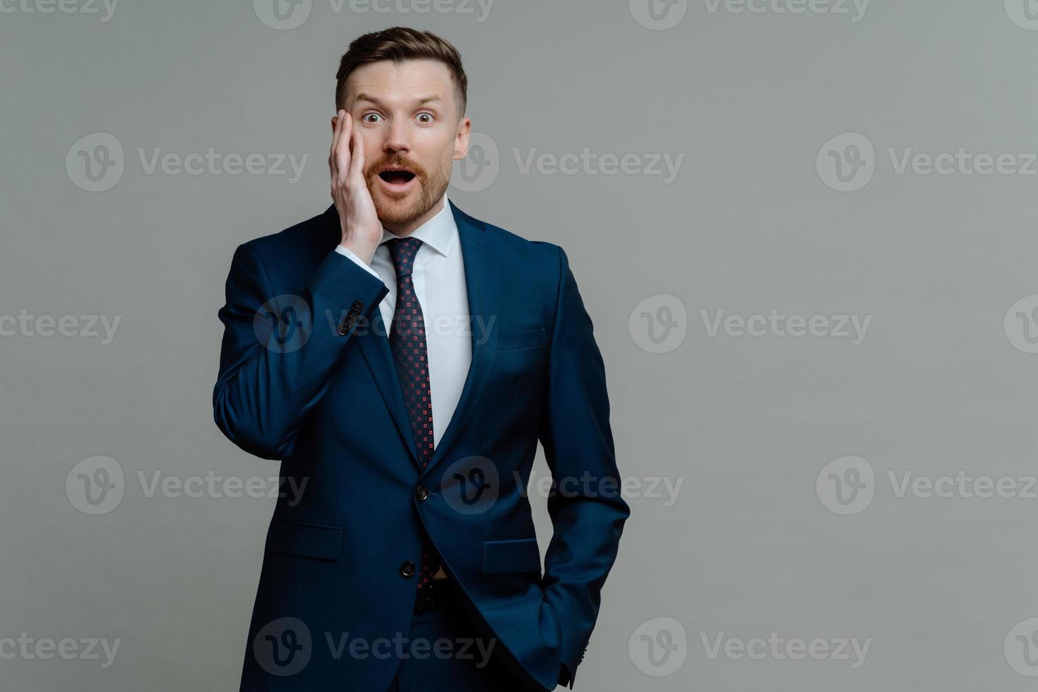 Surprised businessman in suit looking at camera with shocked face expression photo