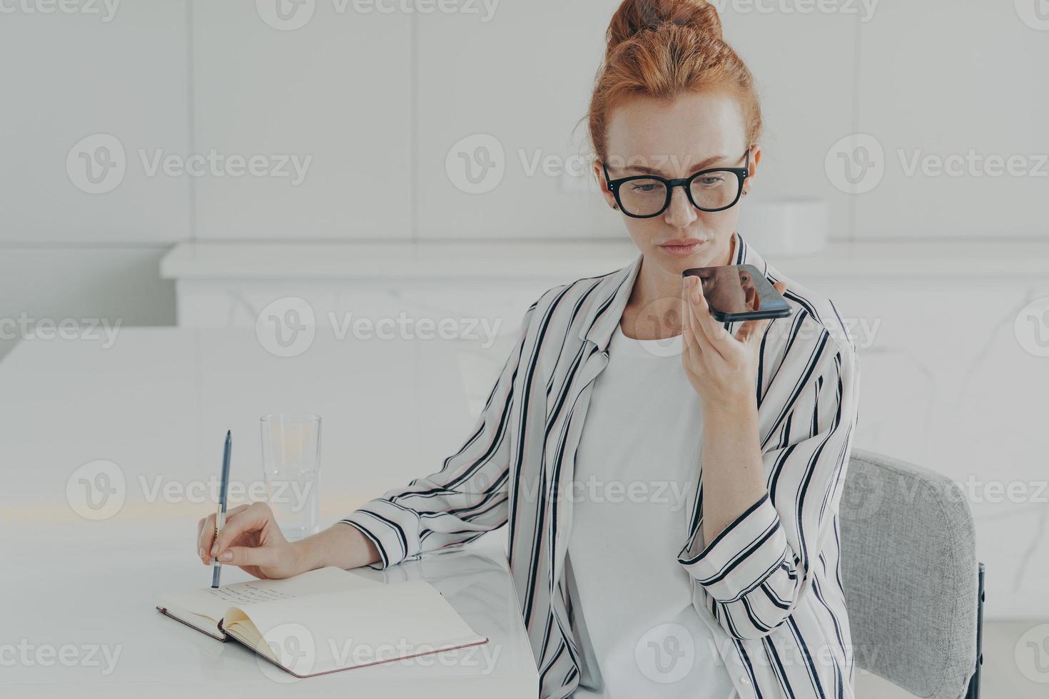 Young focused concentrated ginger woman freelancer using voice