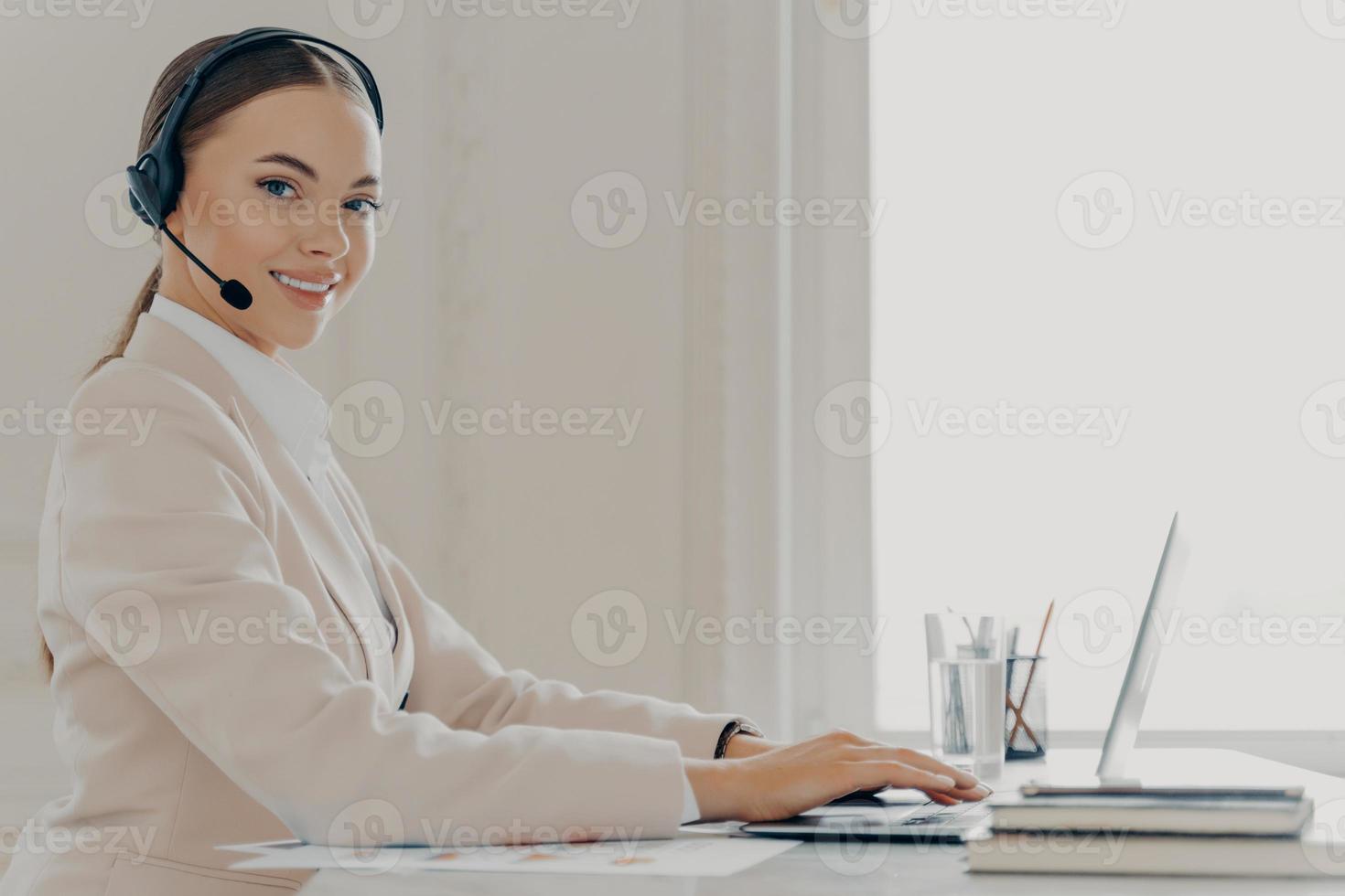 agente sonriente del centro de llamadas en el cliente de consultoría de auriculares foto