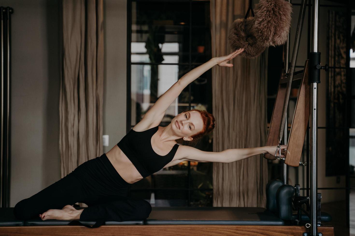 bella mujer haciendo ejercicio y estirándose en cadillac reformer foto