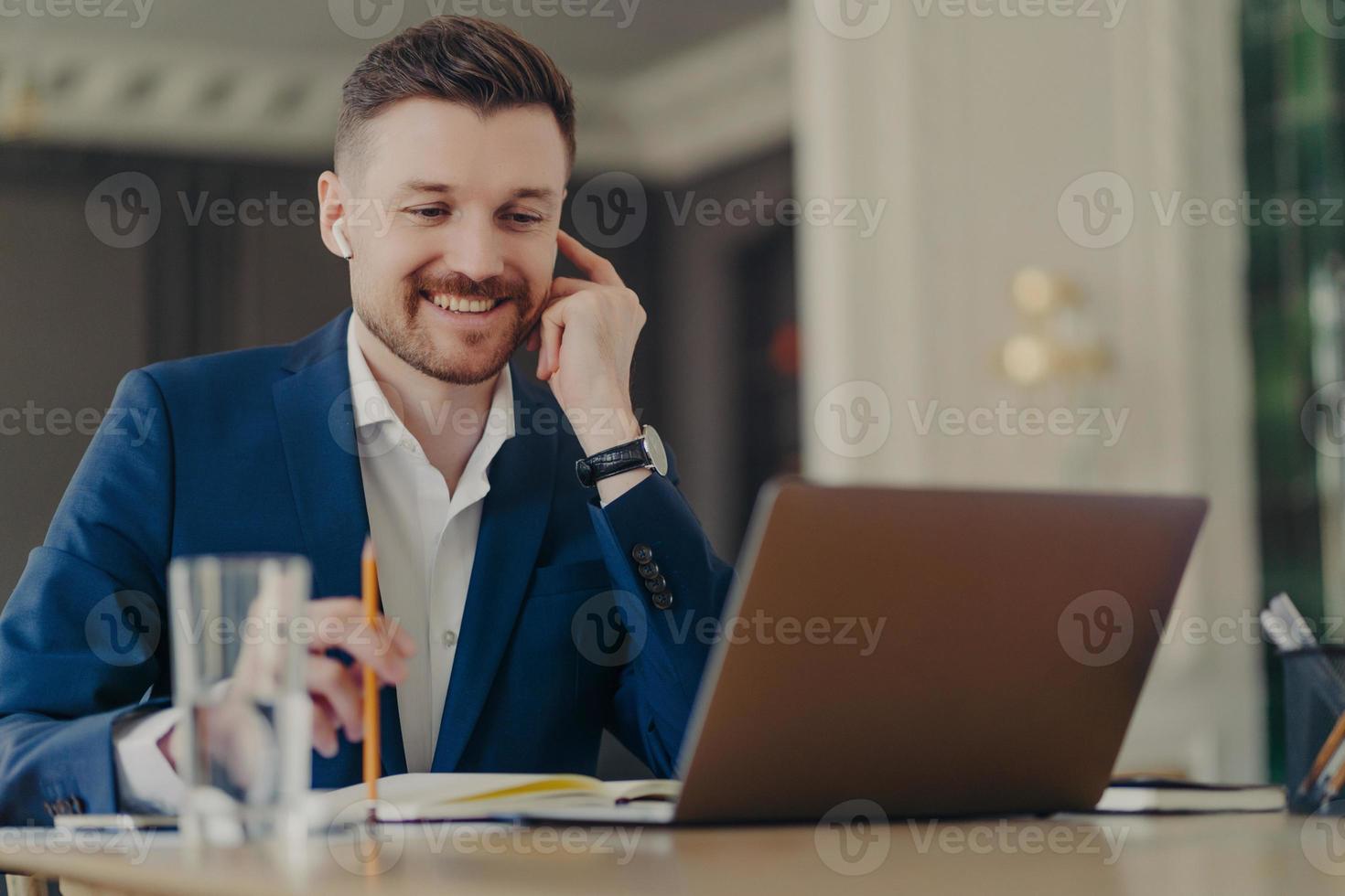 exitoso director ejecutivo feliz teniendo una reunión en línea, usando una computadora portátil y auriculares foto