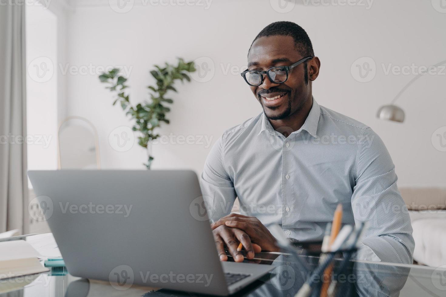 Online freelance remote job. African american man is speaking in front of camera of pc. photo