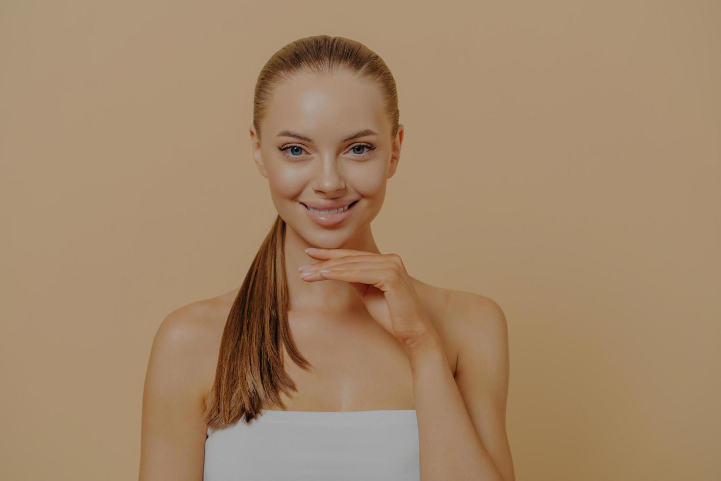 primer plano de una joven mujer feliz tocando la piel facial saludable después del procedimiento de belleza, disfrute de la rutina de cuidado de la piel foto