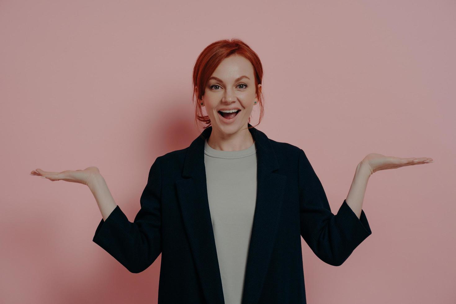 Young happy excited red-haired caucasian woman smiling while comparing two products photo