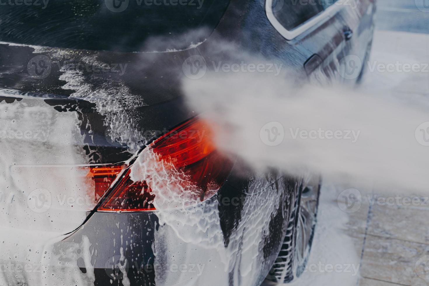 Vehicle covered in white soapy foam during regular wash outdoors photo