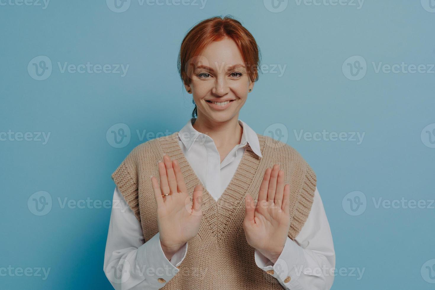 Positive young 30s red haired woman saying no while standing isolated on blue wall background photo