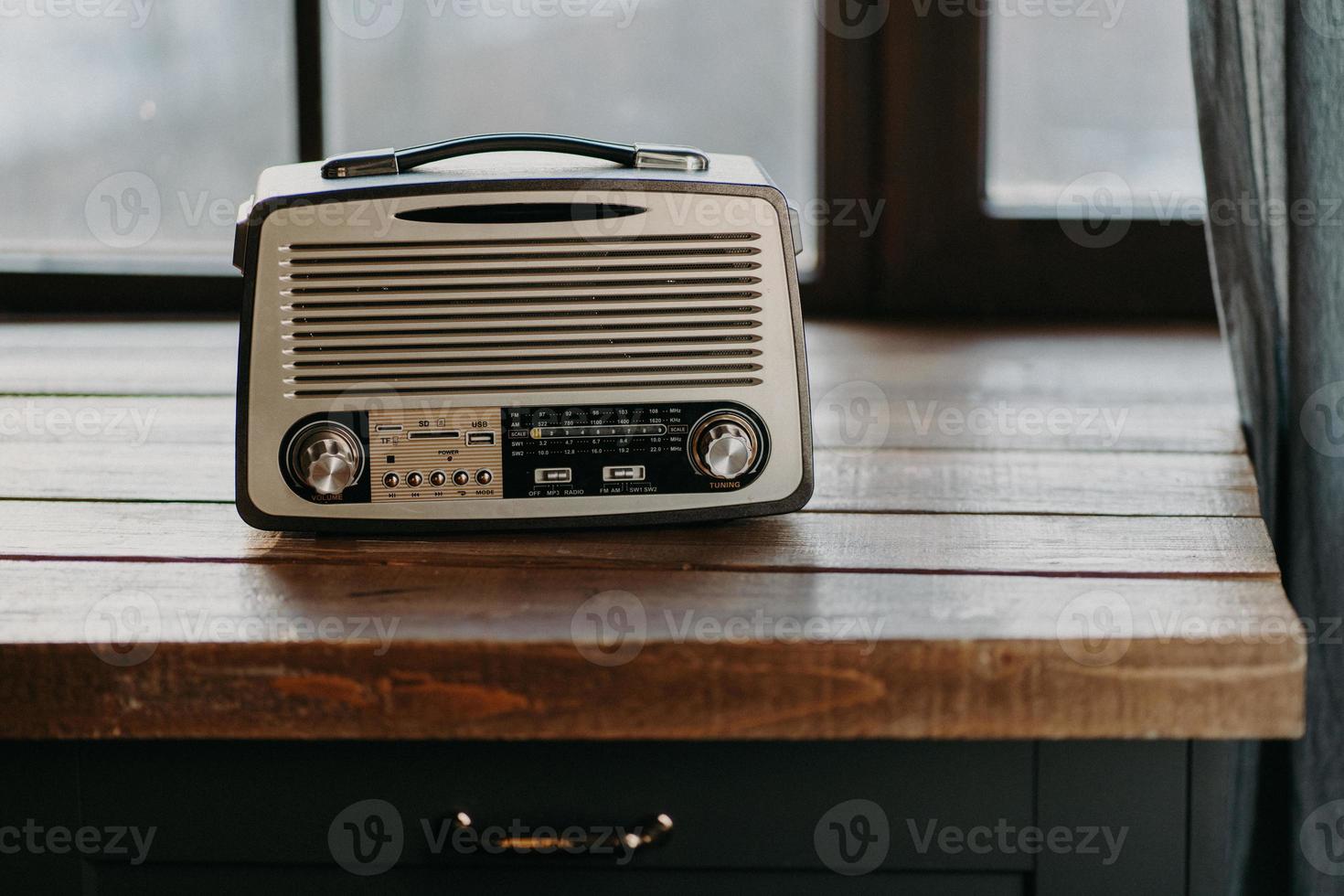 Retro vintage radio on wooden table surface near window. Back to 80s. Music nostalgia and old technology concept. Antique recorder photo