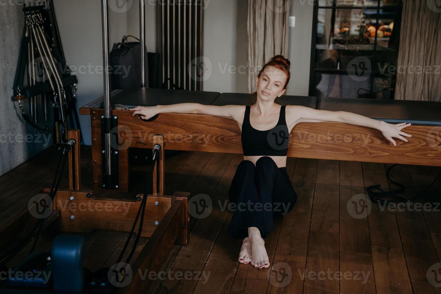 Una joven en forma descansando después de entrenar en reformador de pilates foto