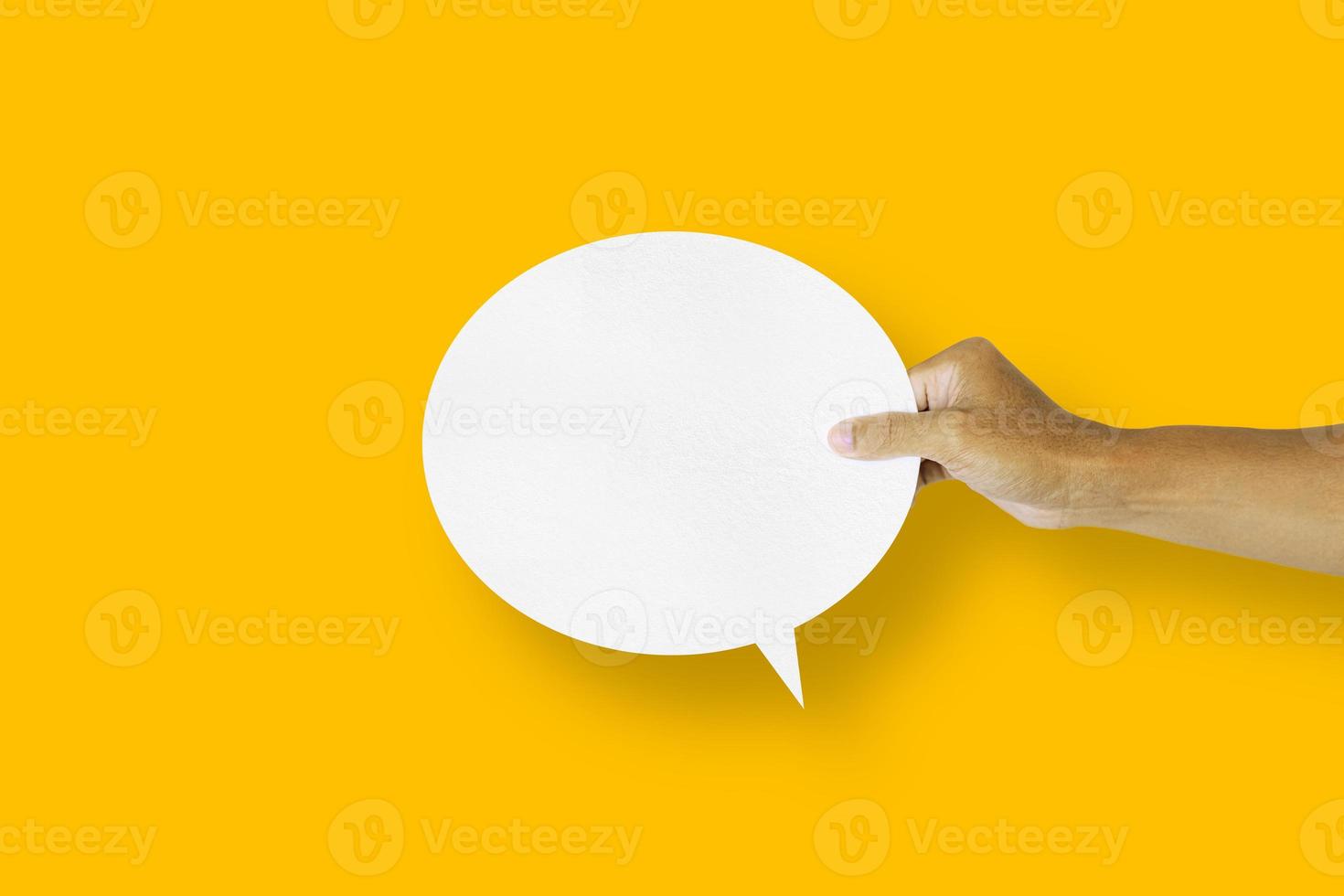 hand holding round white paper balloons speech bubbles isolated on yellow background photo