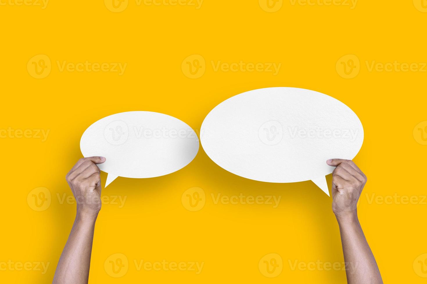 hand holding round white paper balloons speech bubbles isolated on yellow background photo