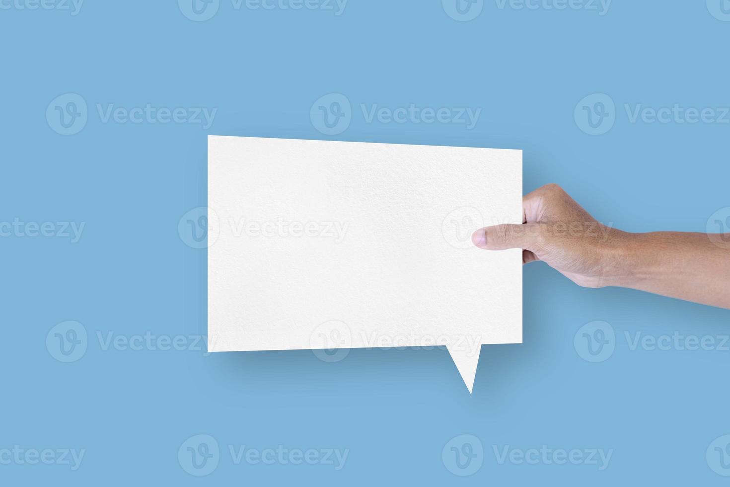 Hand holding a square shaped white paper bubble speech bubble isolated on light blue background. communication bubbles photo