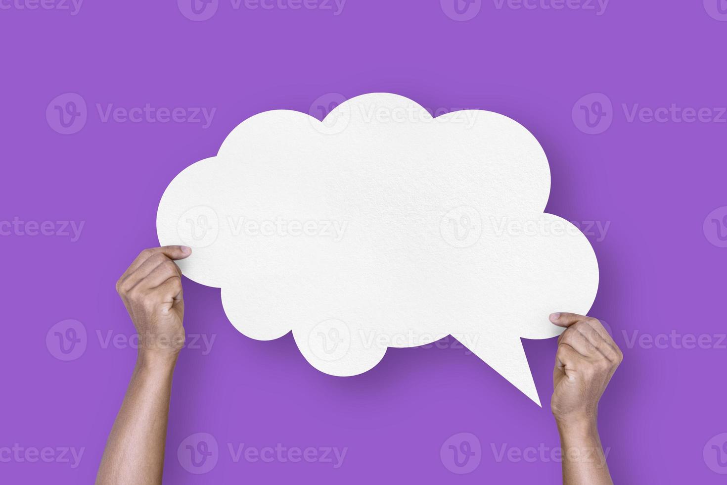 hand holding white paper cloud shape speech bubble balloon isolated on purple background communication bubbles photo