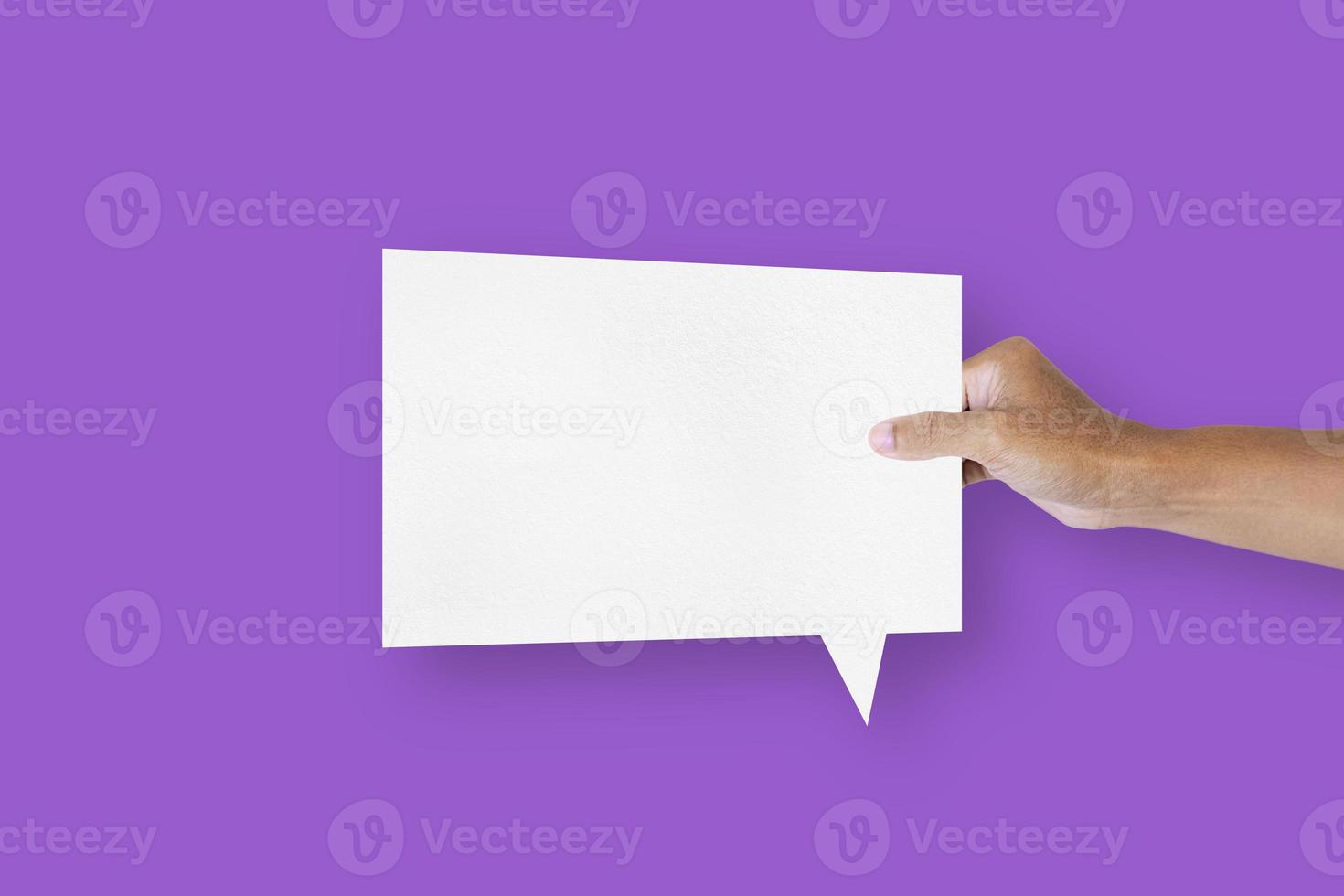 hand holding a square shaped white paper balloons speech bubbles isolated on purple background communication bubbles photo