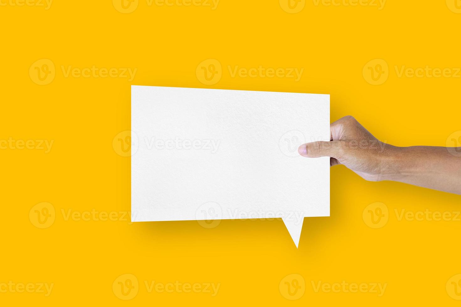 hand holding a square shaped white paper balloons speech bubbles isolated on yellow background communication bubbles photo