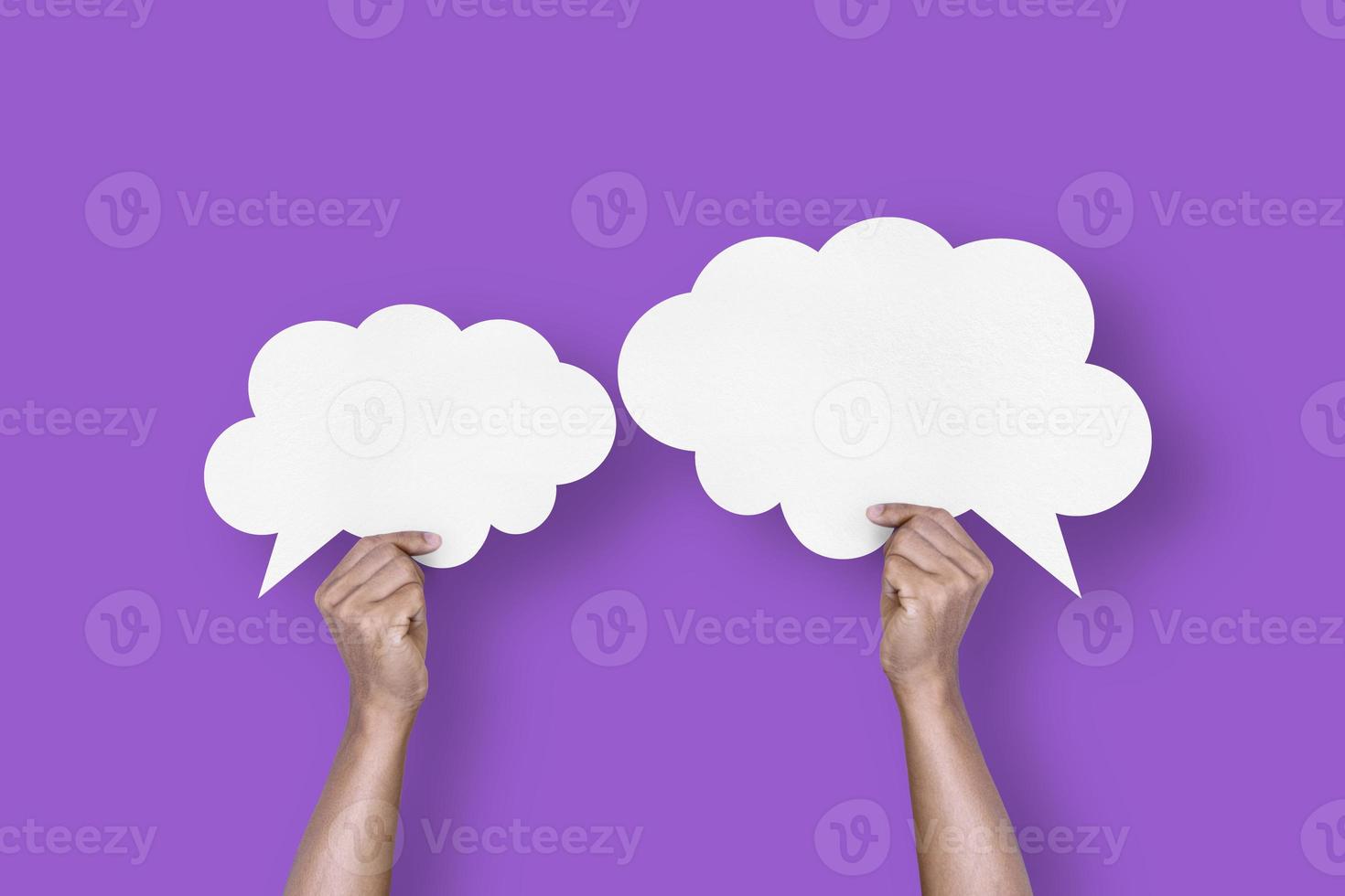 hand holding white paper cloud shape speech bubble balloon isolated on purple background communication bubbles photo