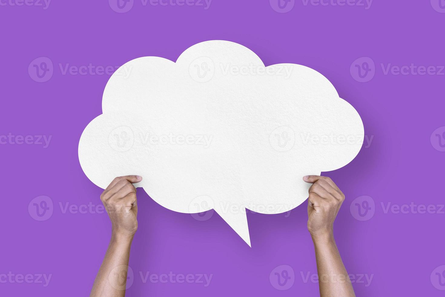 hand holding white paper cloud shape speech bubble balloon isolated on purple background communication bubbles photo