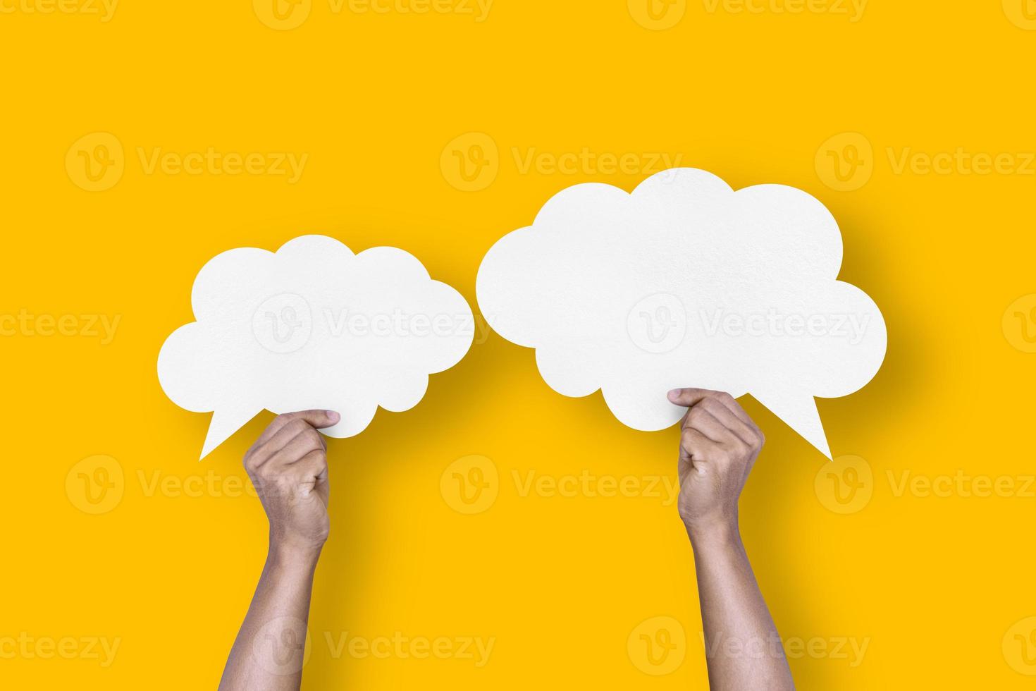 hand holding white paper cloud shape speech bubble balloon isolated on yellow background communication bubbles photo