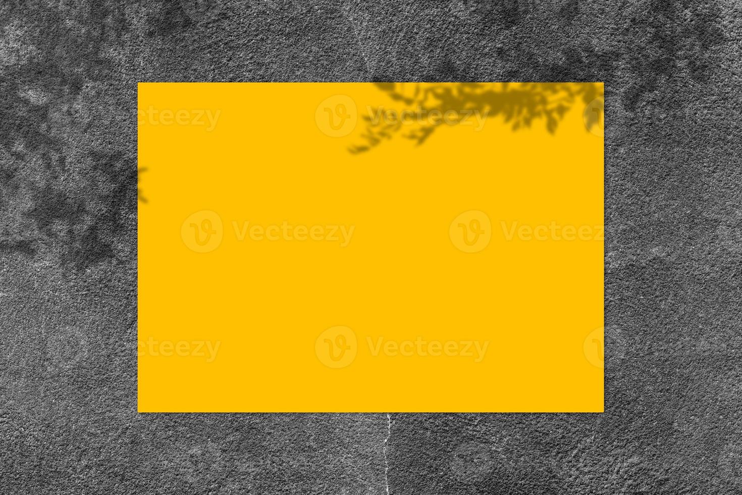 Empty yellow square poster mockup with light shadow on black concrete wall background. photo