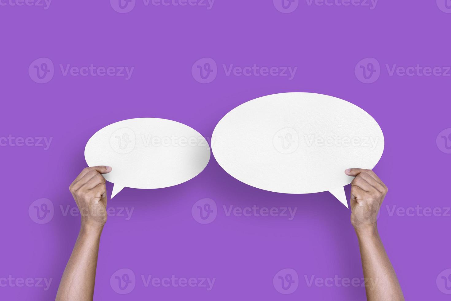 hand holding round white paper balloons speech bubbles isolated on purple background photo