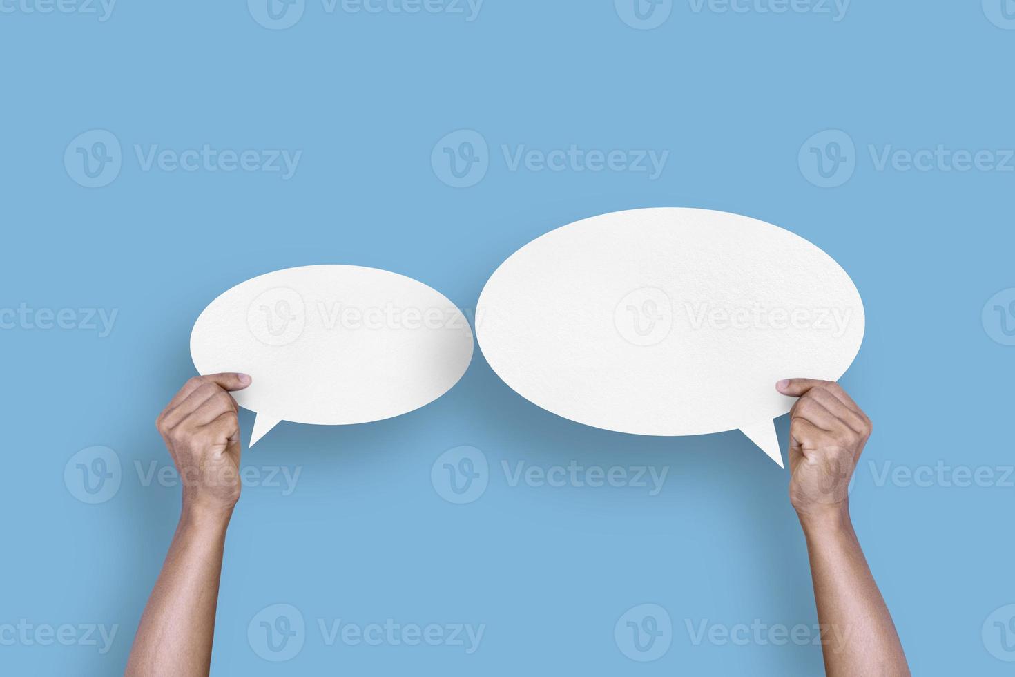 hand holding round white paper balloons speech bubbles isolated on light blue background photo